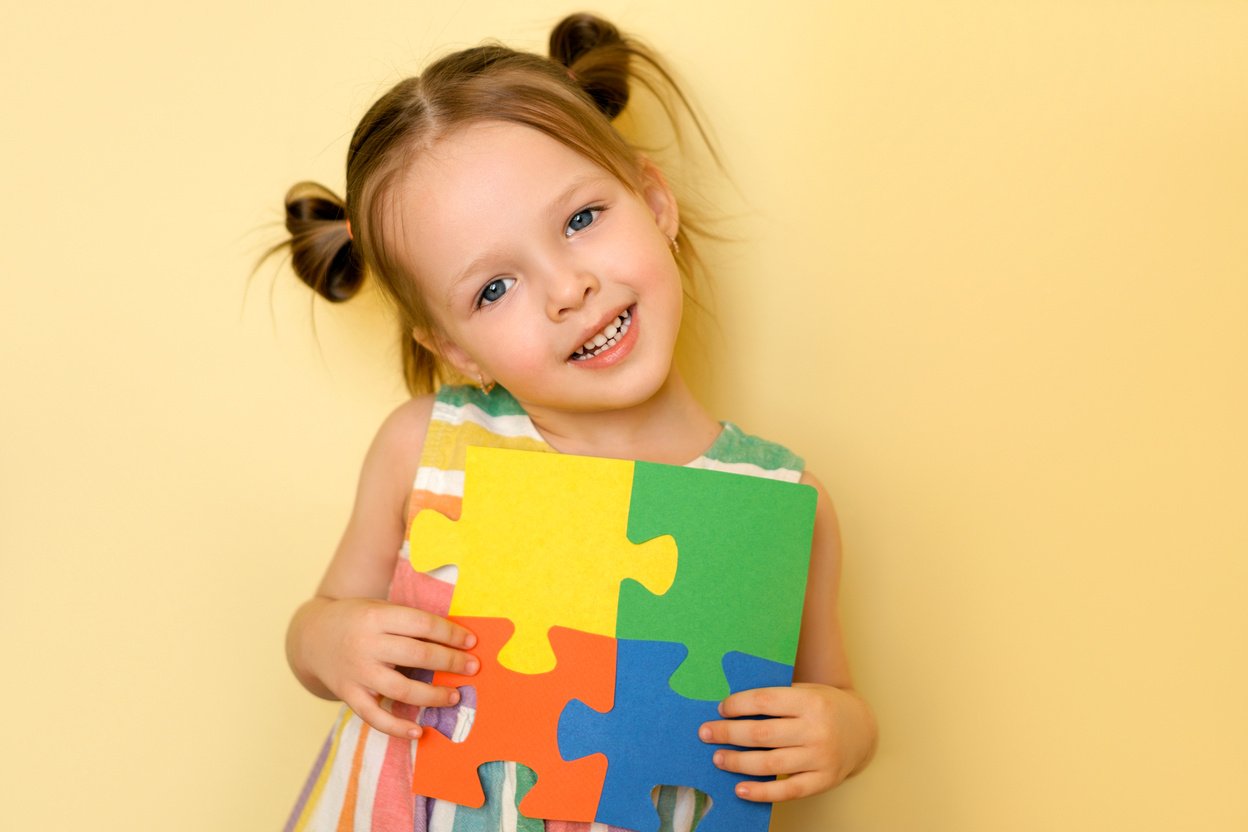 Girl shows the pieces of puzzles, support for people with autism syndrome.